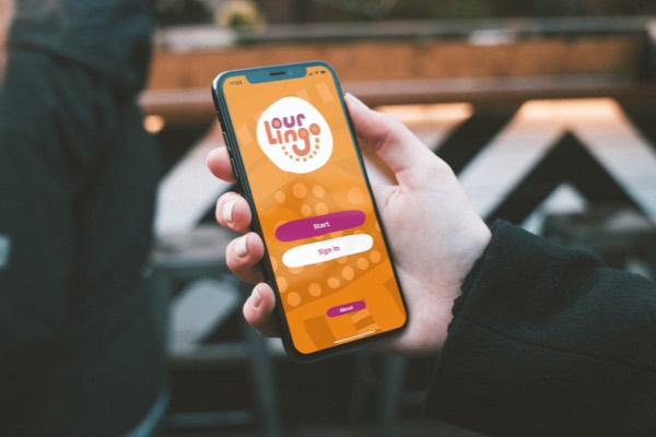 Ourlingo iOS app running on a phone held by a person